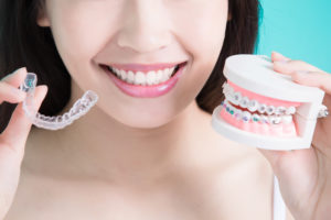 Young woman holding display of wire braces and Invisalign